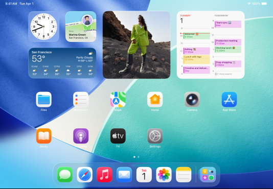 Tre iPad-modeller i vandret position. Den midterste model er foran de andre. Apple Pencil er fastgjort magnetisk ovenpå den midterste model. Den midterste skærm viser hjemmeskærmen med farverige appikoner med Liquid Glass-effekt. Skærmen til venstre viser Billedfremviser-appen. Skærmen til højre viser hjemmeskærmen med filer spredt ud i en vifte fra Dock.